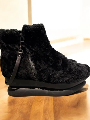 Svarta fluffiga boots med dragkedja i skinn - Unika svarta boots Gram med fluffig päls och chunky platt sula. Skorna har dragkedja på sidan och dekorativ rem i skinn. Perfekta för dig som vill sticka ut och hålla värmen under höst och vinter. Nypris 2500kr