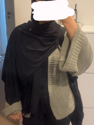 Grön  stickad kofta med vida ärmar - Säljer en oversized grå stickad kofta med breda, långa ärmar och ribbade muddar. Koftan har ett snyggt rutmönster i stickningen och är öppen framtill utan knappar. Perfekt att slänga över en t-shirt eller hoodie för en chill look. Jag brukar ha storlek S men detta är storlek M då jag villa ha lite mer oversize 