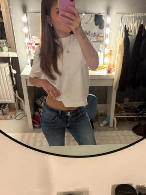 Blå bootcut jeans med låg midja - Säljer ett par klassiska blå jeans med bootcut och låg midja. Jeansen har en snygg tvätt, dubbla knappar i midjan och fickor med lock och knapp bak. Perfekta för dig som tycker om en trendig look med sköna kläder. Har använt ett fåtal gånger men de är väldigt fina och det är en likande jeans modell som true religion 💕