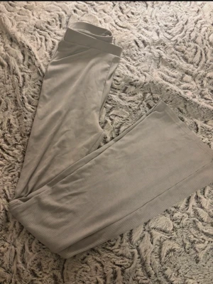 Grå ribbade leggings - Säljer ett par grå leggings med ribbad struktur. De har en hög midja och är tighta i passformen, vilket gör dem riktigt bekväma och snygga. Perfekta att matcha med en hoodie eller t-shirt. Materialet känns mjukt och stretchigt mot huden.