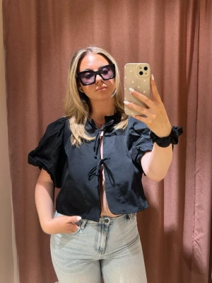 Svart topp  - En svart topp från Gina med knyt snörning framtill, puffiga ärmar som ger en söt och snygg finish🫶🏻