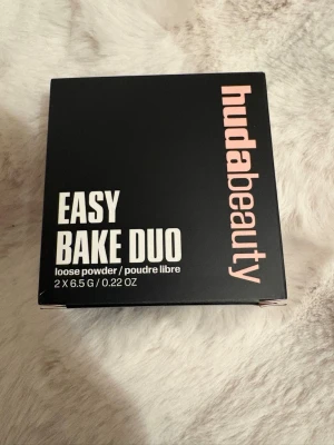 Huda Beauty Easy Bake Duo puder - Säljer Huda Beauty Easy Bake Duo loose powder i färgerna Cherry Blossom Cake och Peach Pie. Tvådelad förpackning med transparent lock, puder i rosa och persikoton. Perfekt för att sätta sminket och ge en matt finish. Innehåller 2 x 6,5 g.