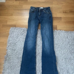 Blå bootcut jeans  - Snygga blå jeans från Zara med klassisk femficksdesign och bootcut-ben. Jeansen har en medelhög midja och är tillverkade i slitstarkt denimmaterial.
