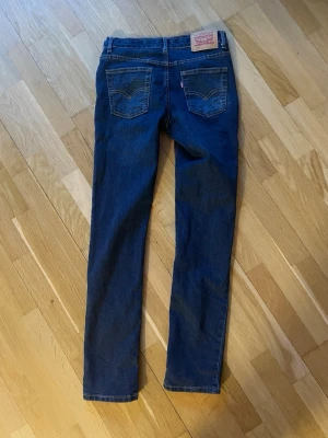 Levi's 510 mörkblå jeans - Snygga Levi's 510 jeans i mörkblå tvätt med klassiska fem fickor och röd Levi's-tag på bakfickan. Modellen har en slim passform och raka ben, tillverkade i slitstarkt bomullsmaterial med lite stretch för extra komfort. Storlek 164 (14 år)