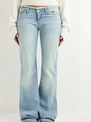 Ljusblå bootcut jeans med rå kant - Säljer ett par ljusblå bootcut jeans med låg midja och rå, fransad kant upptill. Jeansen har klassisk femficksdesign och är tillverkade i mjukt denimtyg. Passformen är loose och benen är utsvängda för en cool vibe. Korta i längden 