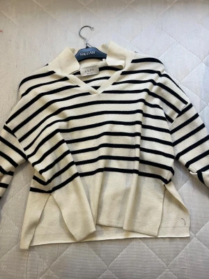 Randig vit och svart stickad tröja ADPT - KappAhl - Säljer en snygg stickad tröja från ADPT i vit med svarta ränder. Tröjan har v-ringad hals och långa ärmar, samt en lite loose passform. Perfekt för dig som gillar klassisk stil med en modern twist.