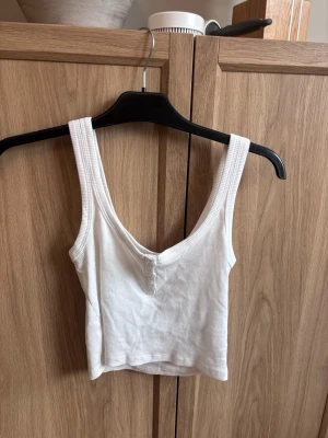 Vit ribbad topp - Säljer en vit croppad linnetopp från 157 i storlek XS. Toppen är ribbad och har tre små vita knappar framtill