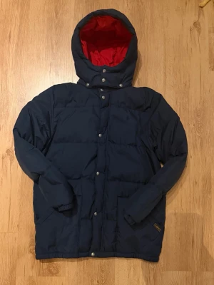 Ralph Lauren mörkblå dunjacka – Barn XL (passar S-M herr) – Superbra skick – Original - Säljer en Ralph Lauren dunjacka i mörkblå/navy, storlek barn XL, som passar herr M–L. Jackan är i superbra skick, sparsamt använd och mycket väl omhändertagen – inga fläckar, inga hål och inget slitage. • Märke: Ralph Lauren • Färg: Mörkblå / Navy • Storlek: Barn XL • Passar: Herr M–L • Skick: Superbra skick • Material: Dun • Säsong: Höst / vinter • Passform: Normal