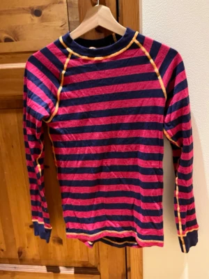 Ulltröja - Väl använd ulltröja i bra skick. Randig i rosa och mörkblå med orangea sömmar. Skön, stretchig och bekväm. Djur och rökfritt hem. Storlek 160 från Ullmax. Säljes då den är för liten.