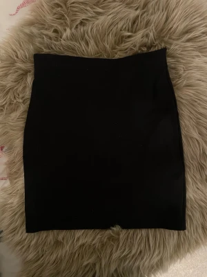 Svart tight kortkjol från Cubus - Enkel och stilren svart kortkjol från Cubus i storlek XS. Kjolen har en tight passform och är gjord i ett mjukt, stretchigt material som sitter snyggt på kroppen. Perfekt att matcha med en crop top eller oversized tröja.