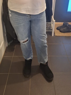 Ljusblå jeans med hål på knät - Säljer ett par ljusblå jeans med klassisk femficksdesign och ett snyggt hål på ena knät. Jeansen har rak passform och är tillverkade i jeansmaterial. Perfekt för dig som gillar en avslappnad och trendig stil.  Shein stl L 