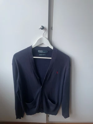 Ralph Lauren Kofta - En mycket fin Ralph lauren kofta som är i mycket bra skick. Den har den klassiska loggan broderat på bröstet och är mörkblå. Tröjan är i storlek S men passar för både S och M. Hör av er vid minsta fråga och vid snabb affär kan vi justera lita på priset😉
