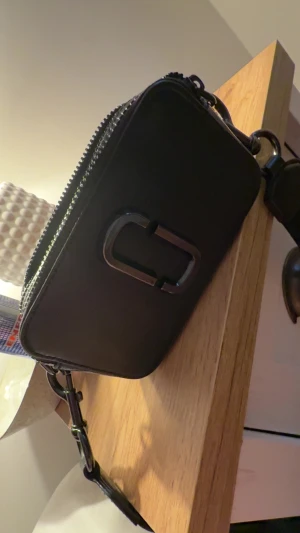 Svart axelväska Marc Jacobs Snapshot Äkta - Säljer en svart axelväska från Marc Jacobs, modellen Snapshot. Materialet är skinn med snygg struktur och logga framtill. Perfekt för dig som gillar klassisk design med coola detaljer. Pris kan disskuteras, ÄKTA pris 1099, Nypris 3800