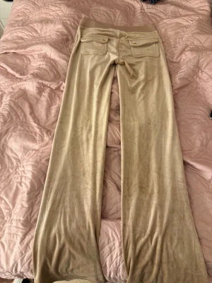 Beige mjukisbyxor Juicy Couture XS - Säljer ett par beige mjukisbyxor från Juicy Couture i storlek XS. Byxorna är beige färgade med guldiga detaljer. Materialet är mjukt och skönt, perfekt för chill dagar. Klassisk Juicy Couture-stil. Jag har aldrig tvättat de men använt en gång då jag testade men de ej passade mig.