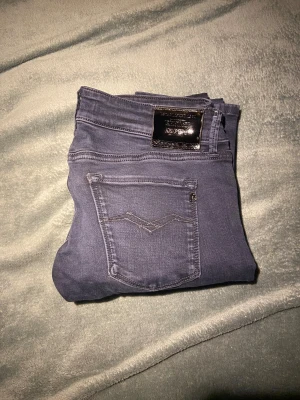 Mörkblå Replay jeans, 29/32 - Snygga mörkblå jeans från Replay i modellen midwaist. Klassisk femficksdesign med diskret broderad bakficka och metallmärke bak i midjan. Jeansen har en smal passform och är tillverkade i mjukt bomullsmaterial med stretch för extra komfort.