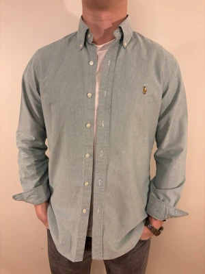 Ljusgrön Ralph Lauren skjorta - En stilren skjorta från Ralph Lauren. Second hand men i väldigt fint skick ✨ Tvättad och struken – redo att användas direkt.  Perfekt för både vinter och sommar, funkar både uppklätt och casual. Inga defekter och regular fit.  Storlek 👔: M Nypris 💰: ca 1 300 kr