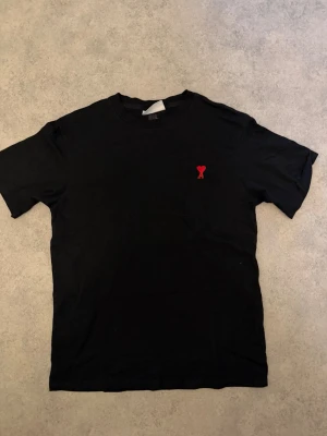Svart t-shirt från AMI med rött hjärta - Svart t-shirt från AMI. Riktigt bra skick i storlek L men som sitter mer som M. Nypris är ca 900-1000kr