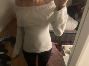 Vit offshoulder stickad tröja - Säljer en vit stickad tröja med offshoulder-design och bred ribbad kant upptill. Tröjan har lång ärm och sitter tight mot kroppen, perfekt för dig som gillar en stilren och trendig look. Passar dig som vill ha något snyggt och bekvämt till vardags.