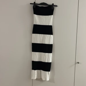 Svartvit randig långklänning M - Säljer en snygg långklänning med breda svarta och vita ränder. Klänningen är ärmlös och har en tight passform med ribbad struktur i materialet. Perfekt för dig som gillar en stilren och modern look. Passar även S
