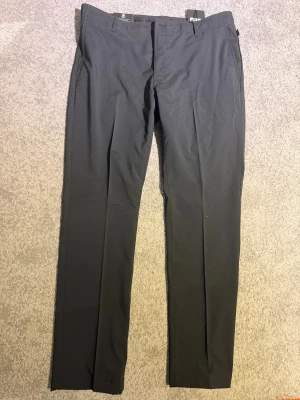 Svarta byxor från Abacus Drycool - Säljer ett par svarta byxor från Abacus. Byxorna har klassisk rak passform, bälteshällor och sidofickor. Perfekta för dig som vill ha stilrena och funktionella byxor med modern känsla på golfbanan.