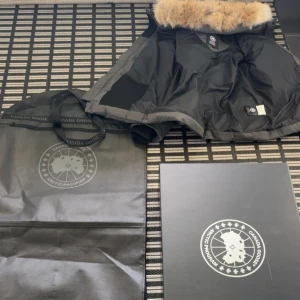  Canada Goose Wyndham (kvitto finns) - Säljer en grå dunjacka från Canada Goose med klassisk patch på ärmen. Jackan har huva med avtagbar päls, dragkedja och knappar framtill samt ribbade muddar. Allt ingår. Använd en vinter, väldigt bra  skick. Finns digitalt kvitto!!! PRISET ÄR DEFINITIVT INTE 7500kr, utan det är för ögat att checka in annonsen.  KOM MED BUD 