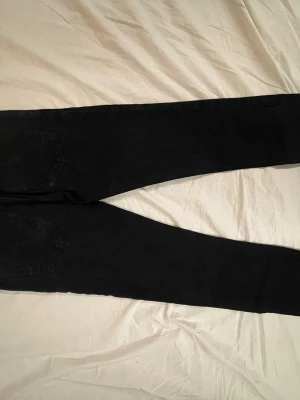 Nudie jeans - Säljer ett par svarta Nudie jeans med klassisk femficksdesign. Byxorna har smal passform och är tillverkade i stretchigt jeansmaterial. Perfekta för dig som gillar en stilren och enkel look. 