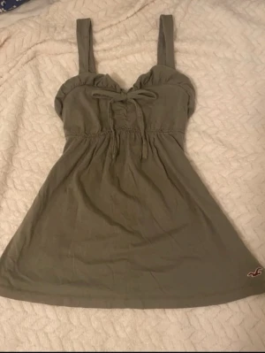 Olivgrön linnetopp från Hollister - Snygg olivgrön babydoll från Hollister med breda axelband och knytning framtill.💖