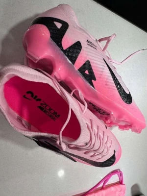Nike Zoom Vapor 15 Elite FG rosa helt nya - Nike Zoom Vapor 15 Elite FG fotbollsskor i en snygg rosa färg med svarta detaljer och stor Nike-logga. Helt nya aldrig använda!