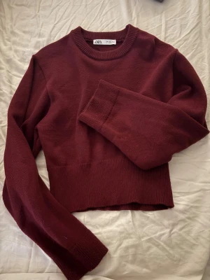 Vinröd stickad tröja från Zara - Snygg vinröd stickad tröja från Zara i storlek L. Tröjan har en croppad passform och är snarare en storlek M/S