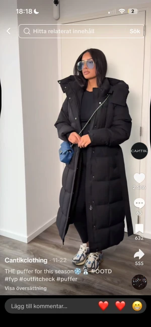 Svart lång pufferjacka med huva - Säljer en svart, lång pufferjacka från Cantikclothing med stor huva och bälte i midjan. Jackan har quiltad design, dragkedja och knappar framtill. Perfekt för kalla dagar och har en loose passform som ger en chill vibe. Storlek M/L