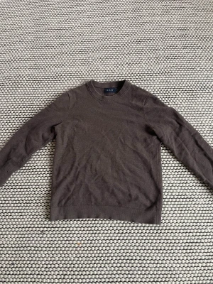 Riley långärmad tröja - Snygg och stilren stickad tröja från Riley i mörkbrun färg. Klassisk modell med rund hals som passar både till vardag och mer uppklädda tillfällen.  Tröjan är knappt använd och i mycket fint skick utan tydliga slitage. Observera att den är liten i storleken, passar bäst för dig som vanligtvis har XS eller liten S.