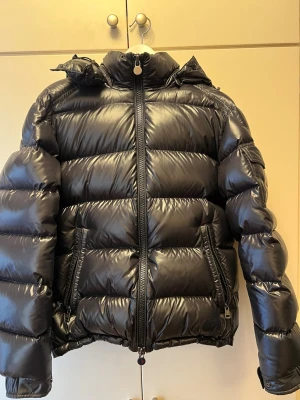 Svart Moncler Maya - Säljer en svart moncler Maya storlek 2 (M). Jackan är i bra skicka (8/10), finns mindre defekter bild 6 och 7. Jackan är inköpt från NK, kvitto och tag finns. Nypris: 18 000kr   