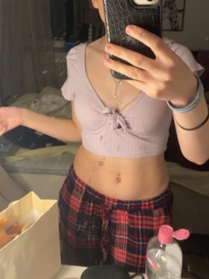 Ljuslila croppad topp från SHEIN - Supersöt ljuslila croppad topp från SHEIN i ribbad bomullsblandning. Toppen har korta ärmar, v-ringning och en snygg knyt-detalj framtill. Perfekt till höga jeans eller kjol för en trendig look.