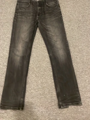 Svarta slim fit jeansbyxor 28/30 - Säljer ett par svarta jeansbyxor i rak modell med snyggt tvättad look. Klassisk femficksdesign och normal passform. Perfekta till vardags för dig som gillar stilrena och enkla jeans.