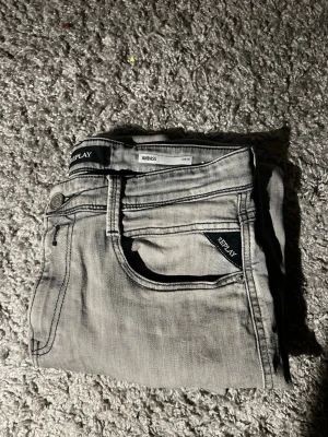 Replay Anbass jeans - Säljer ett par Replay Anbass jeans i snygg ljusgrå färg. Slim fit och ganska bra skick, förutom defekten som finns med på baksidan av jeansen. Men vid användning syns det inte, och det går att fixa. Mitt pris 199kr pga defekten. Kontakta mig om du har frågor.