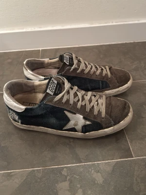 GGDB sneakers med stjärndetalj - Säljer ett par GGDB sneakers med cool stjärndetalj på sidan. Jag säljer för mycket billigt pris på grund av att en liten del av sidan av sulan lossnat, men det är enkelt att laga. Skorna nypris kostar ca 5000 och uppåt. De har en klassisk och snygg sjärnlogga på sidan och skorna passar till många olika outfits! Hoppas du gillar dem👍 Storlek 39