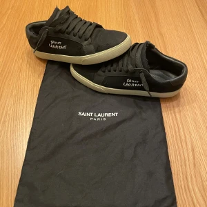 Svarta Saint Laurent sneakers - Svarta sneakers från Saint Laurent. Säljer nu mina ”saints” då dem är lite för små för mig. Jag köpte dem här på Plick helt nya. Bara använda ett fåtal gånger och i stort sätt fortfarande som nya. Skick: 8,5/10 Pris går att diskuteras. Hör av er vid frågor!