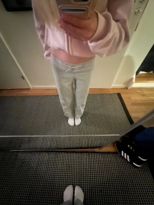 Grå mjukisbyxor med snörning - Säljer ett par ljusgrå mjukisbyxor med resår i midjan och snörning framtill. Byxorna har en rak passform och är tillverkade i mjukt bomullsmaterial. Perfekta för chill dagar hemma eller när du vill vara bekväm. 