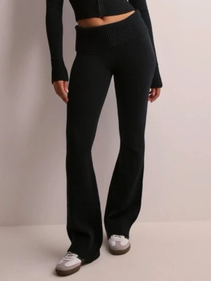 Svarta stickade bootcut byxor - Säljer ett par svarta stickade byxor med bootcut passform och bred ribbad midja. Byxorna är mjuka och stretchiga, perfekta för en chill och trendig look. Passar till sneakers eller chunky boots.