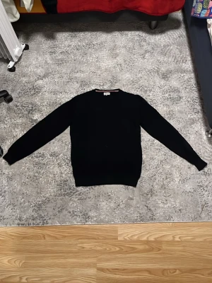 Svart stickad tröja från Moncler M - Säljer en svart stickad tröja från Moncler i storlek M. Tröjan har rund hals, diskret struktur i materialet och en broderad Moncler-logga på bröstet. Klassisk passform och långa ärmar, perfekt till höst och vinter.