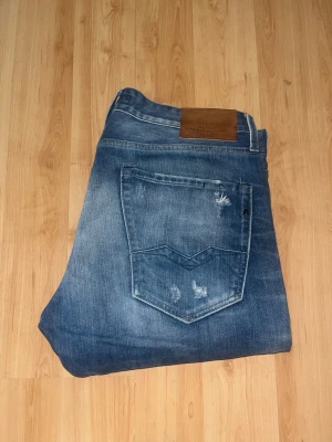 Replay Waitom jeans - Säljer ett par Replay Waitom jeans i klassisk blå tvätt med slitningar och hål på benen. Midja 43cm, längd 108cm. Storlekslappen saknas, men jag bedömer de till W32 L34 - men utgår efter måtten. JAG SKICKAR EJ FLER BILDER NÄR JAG BÄR JEANSEN! för bättre inblick i passformen rekommenderar jag att googla på modellnamnet. För storleksguide kolla måtten noggrant då jeansen alltid kan vara uppsydda heller krympta och jag ej tar emot returer :) 1,1