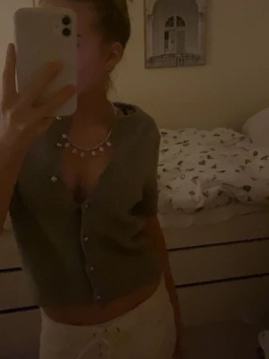 Grå kofta från ZARA med kort ärm - Superfin grå kofta från ZARA med korta ärmar och silvriga knappar. Koftan är stickad och har en croppad passform som ger en trendig look. Perfekt att styla med jeans eller kjol för en chill vibe.