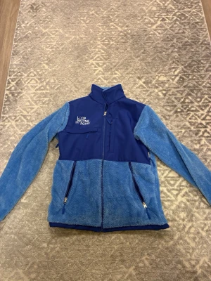 Blå fleecejacka - En mjuk och skön fleecejacka med dragkedja, två praktiska fickor och justerbar midja.  OBS! Jackan är XS men känns större. Passade mig som vanligtvis har S/M