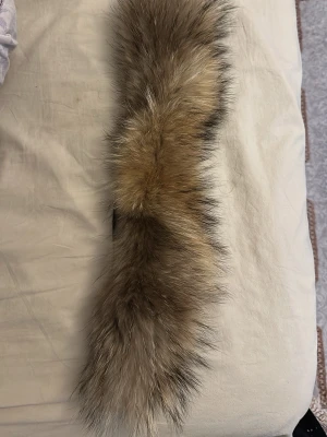 Canada goose päls - Säljer en fluffig pälsdetalj i bruna och beige toner med inslag av svart. Pälsen har en dragkedja på baksidan och passar perfekt som krage eller detalj till jacka eller väst. Pälsen är mjuk och ger en lyxig känsla.