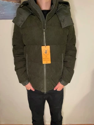 Mörkgrön pufferjacka från Save The Duck - Säljer en mörkgrön pufferjacka från Save The Duck med avtagbar huva och ribbad manchesterstruktur. Jackan har två dragkedjeförsedda fickor fram och hel dragkedja. Perfekt för kalla dagar och har en cool, urban vibe. Nypris 4500 kr. Vid funderingar skriv😁