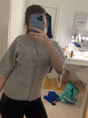 Grå kofta från Gina Tricot - Mysig grå kofta från Gina Tricot i stickat material. Koftan har knappar hela vägen framtill, ribbade muddar och halvlånga ärmar. Perfekt att slänga på sig när det är lite kyligt ute.