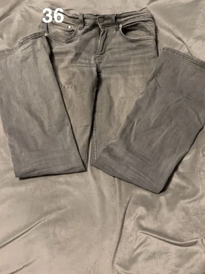 Grå jeans ifrån Gina  - Säljer ett par grå jeans med raka ben och klassisk femficksdesign. Jeansen har normal passform och är tillverkade i mjukt denimtyg. Perfekta för dig som gillar en enkel och clean look.