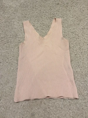 Ljusrosa ribbad linnetopp - Säljer en ljusrosa ribbad linnetopp med v-ringning både fram och bak. Köpt utomlands och ör nästan aldrig använd 