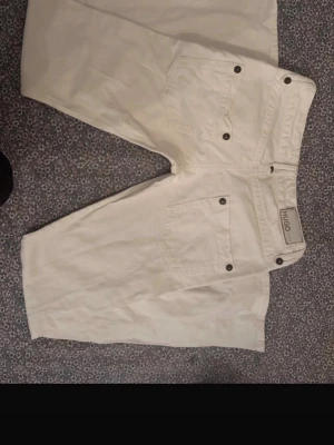 Vita raka jeans från Hugo Boss - Säljer ett par lågmidjade jeans från Hugo Boss Byxorna har silverfärgade nitar och en diskret Hugo Boss-lapp bak i midjan. Vita i denim