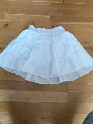 Vit volangkjol i bomull - Söt vit kortkjol med volanger och broderade detaljer. Den har även som så shorts under så man slipper oroa sig💕 